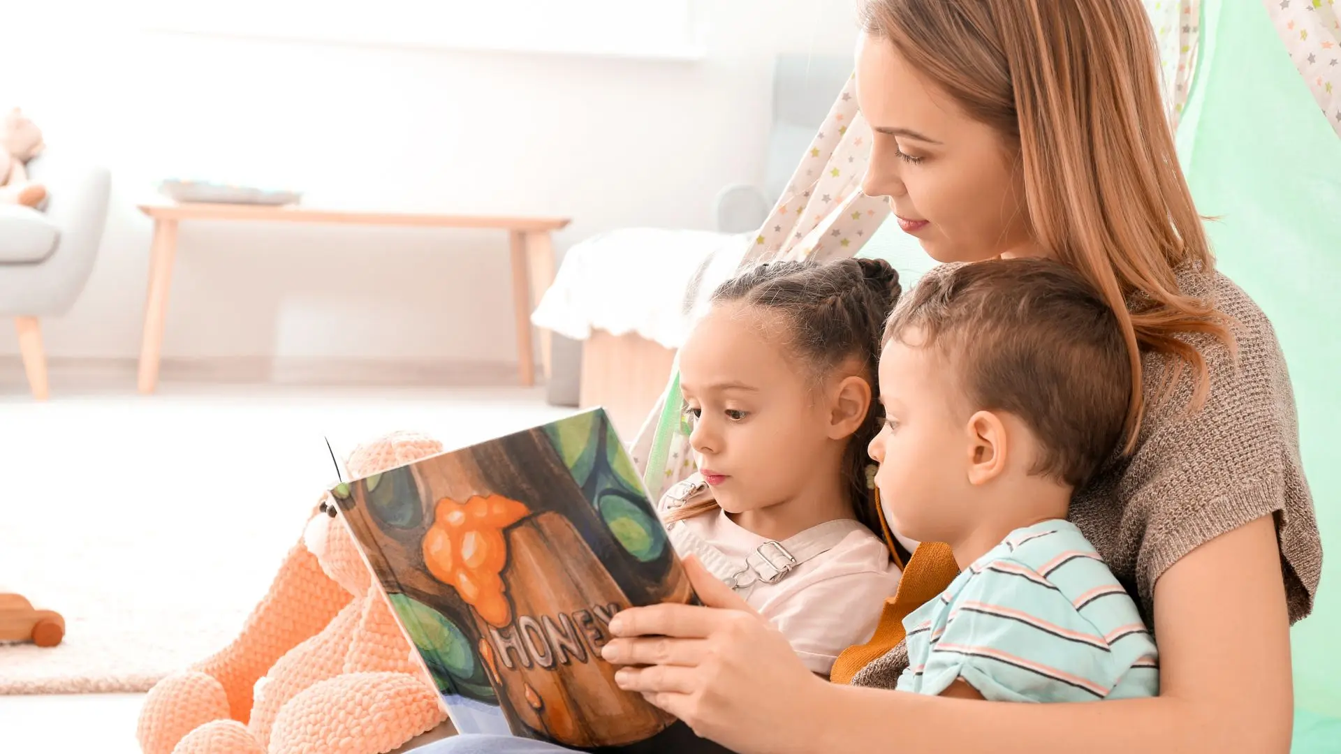 Dos niños leyendo con una mujer